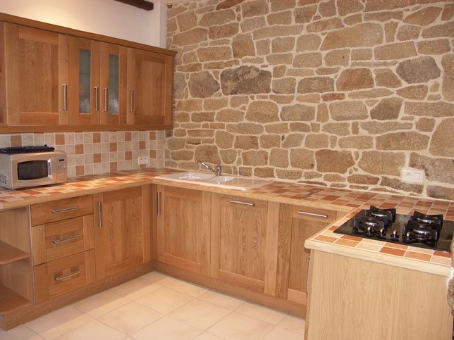 Oak kitchen fitted against a stone wall