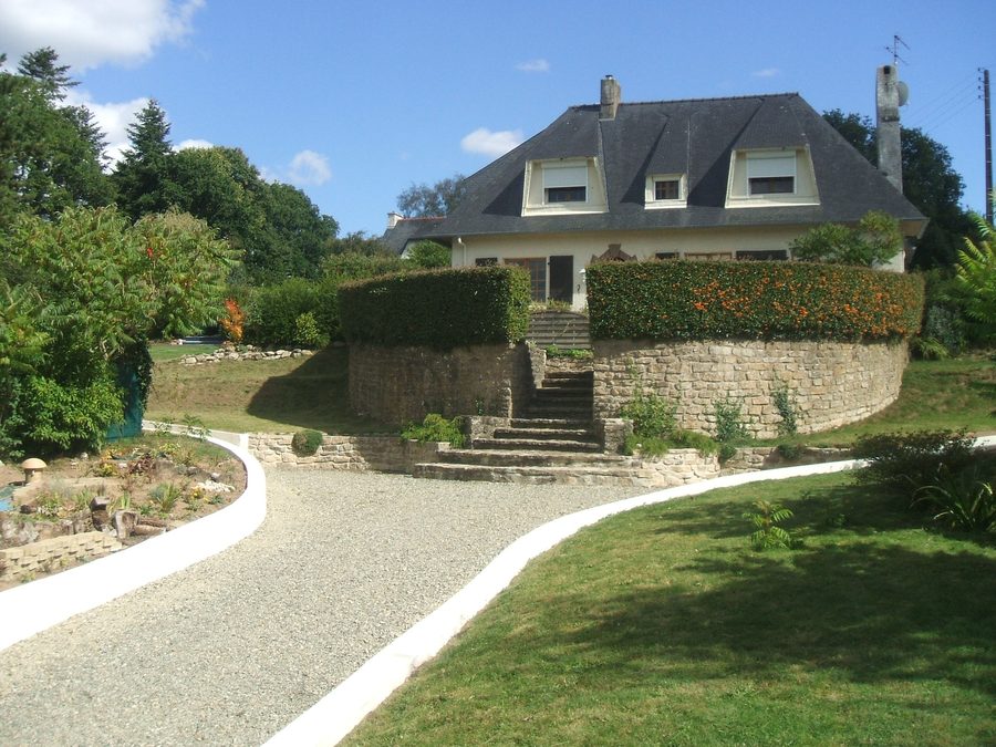 The same entrance, finished: low walls, gravel drive and edging